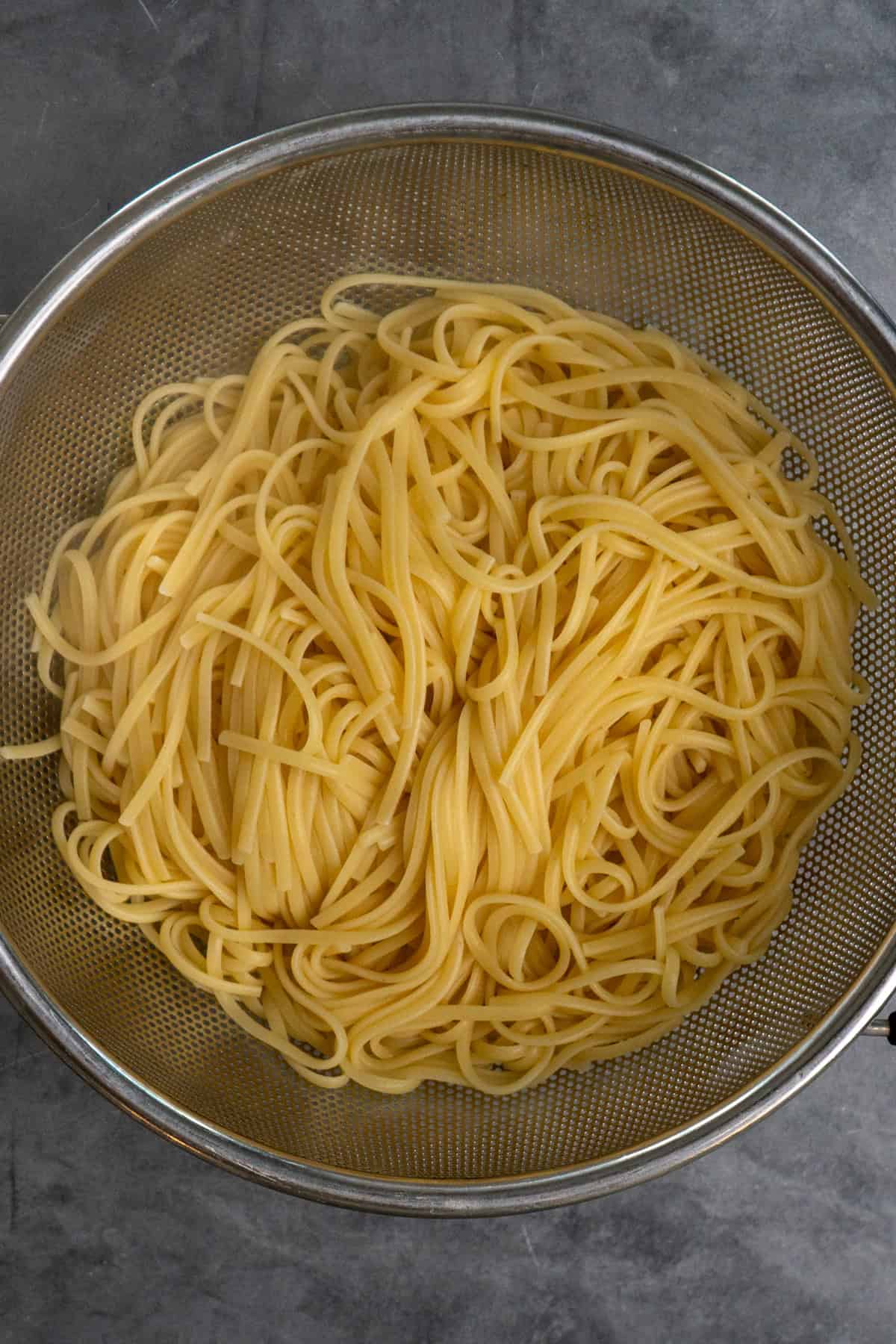 Cooked noodles in a strainer.