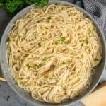 A bowl of garlic butter pasta sprinkled with parsley and parmesan cheese.