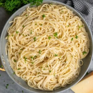 A bowl of garlic butter pasta sprinkled with parsley and parmesan cheese.