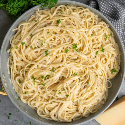 A bowl of garlic butter pasta sprinkled with parsley and parmesan cheese.