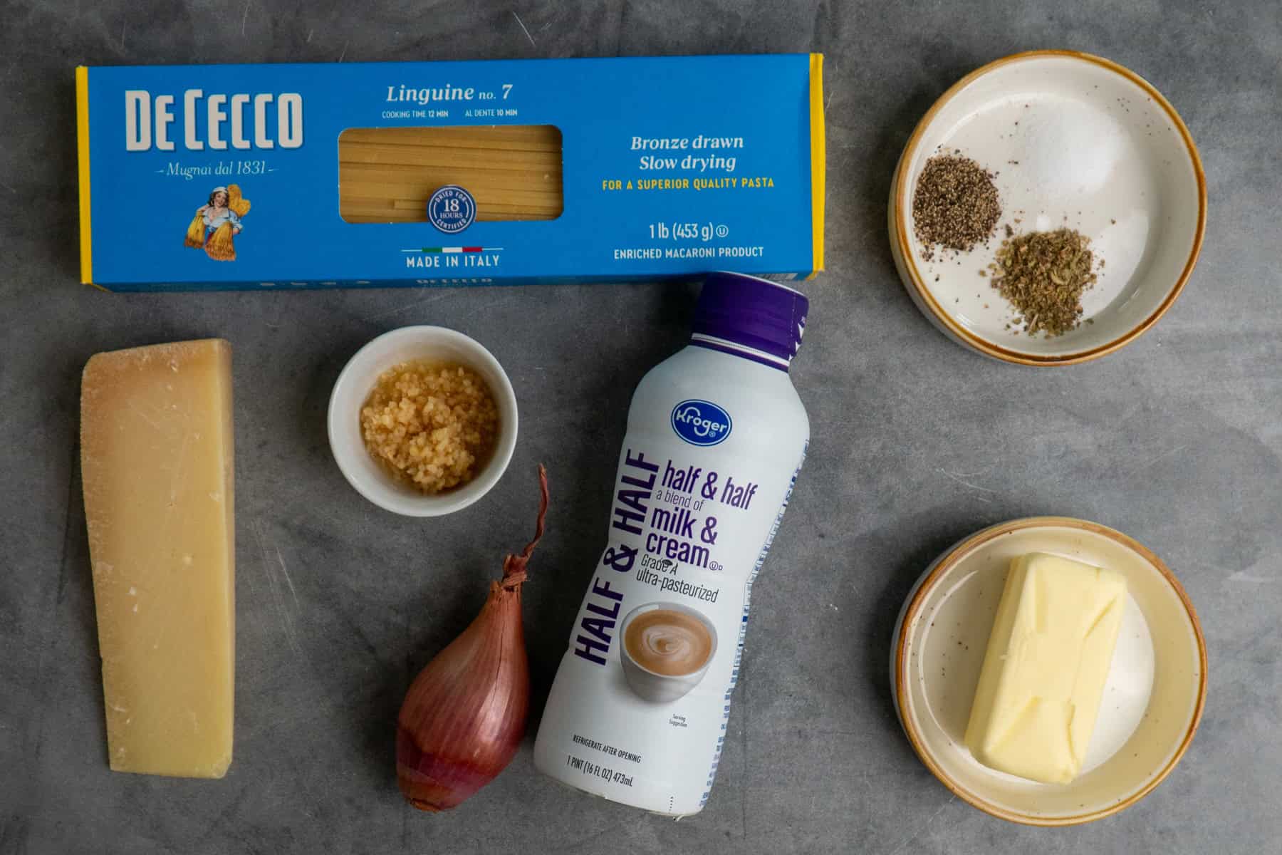 Ingredients to make garlic butter pasta on a gray surface.