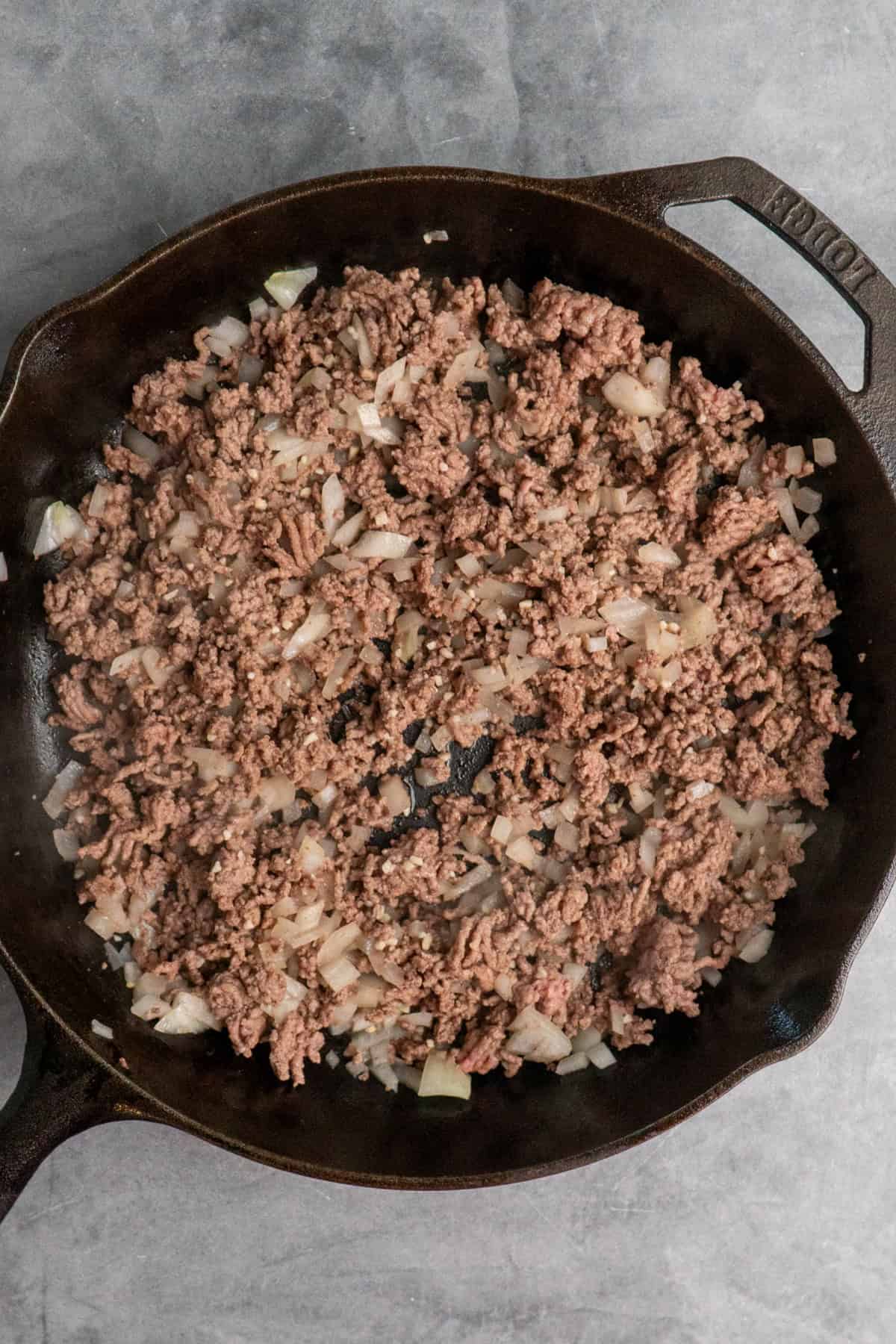Cooked ground beef, onions, and garlic in a skillet.