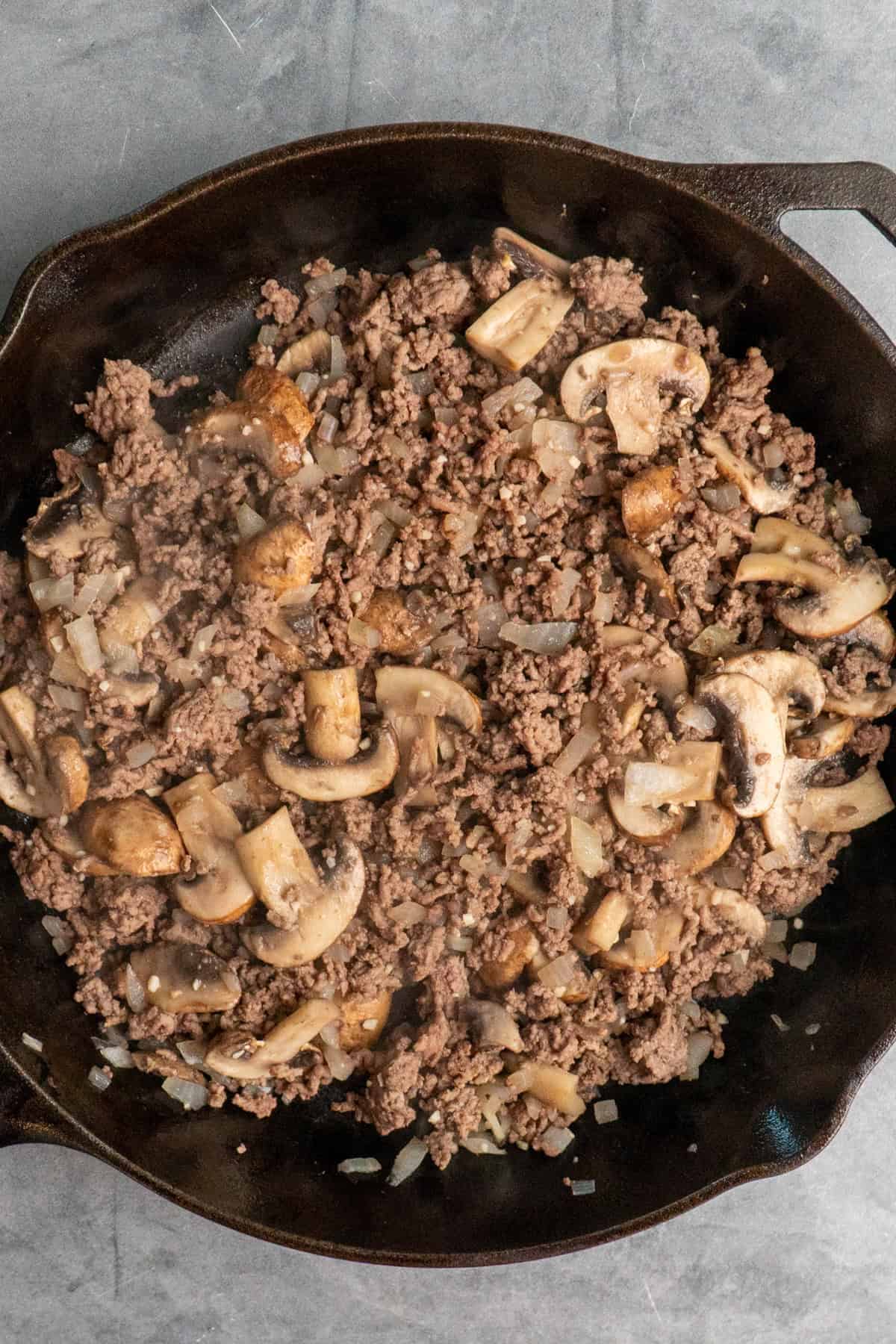 Cooked mushrooms added the meat mixture in a skillet.