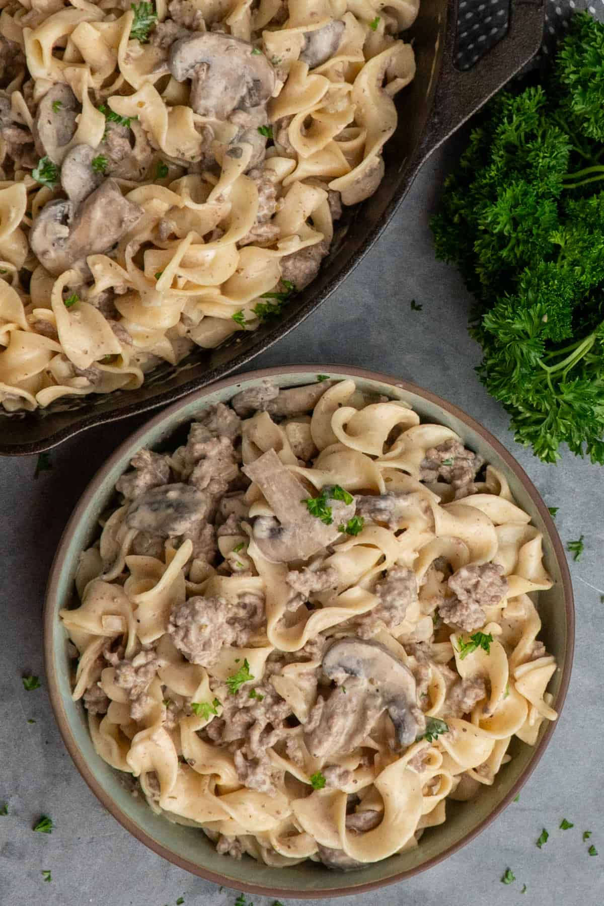 Ground beef stroganoff in a skillet and blue bowl.
