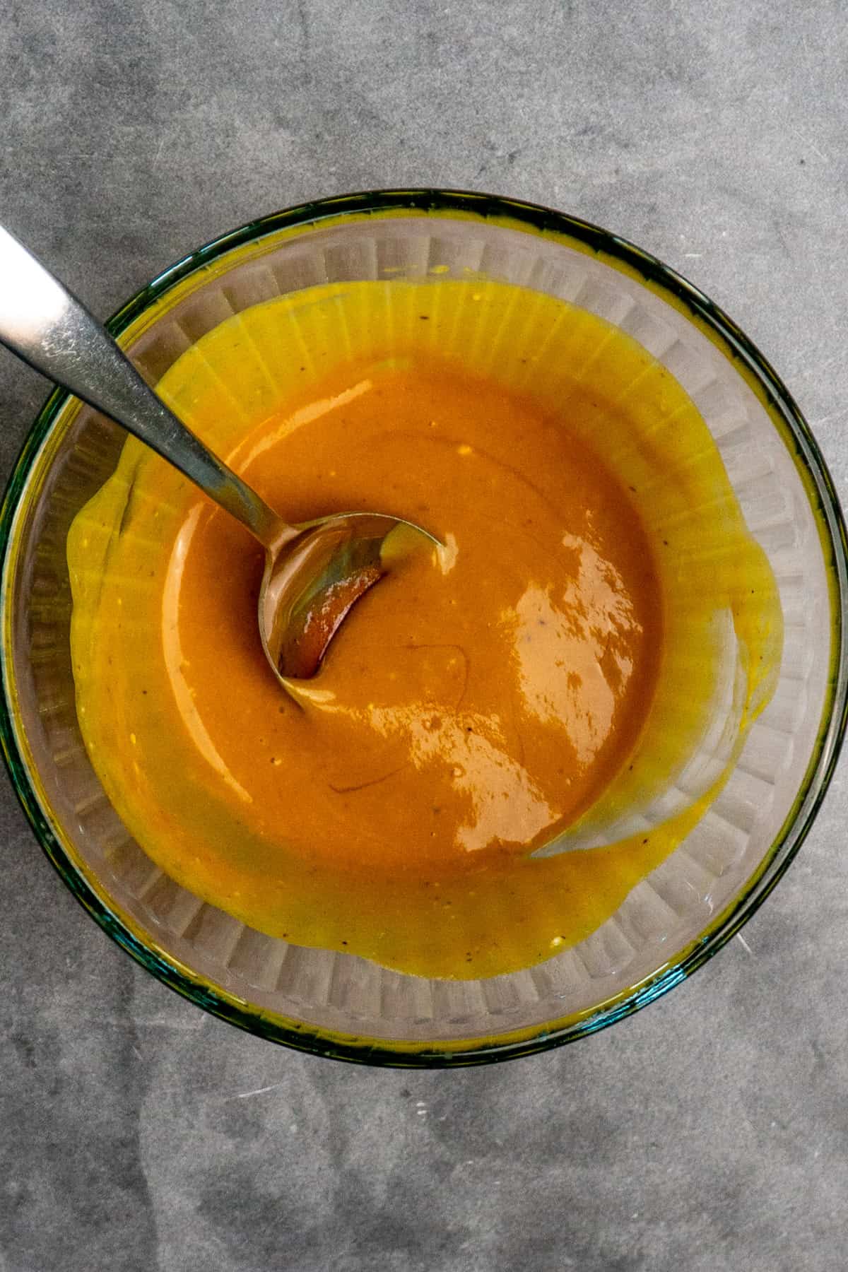 Mayonnaise, mustard, honey and barbecue sauce mixed together in a clear bowl.