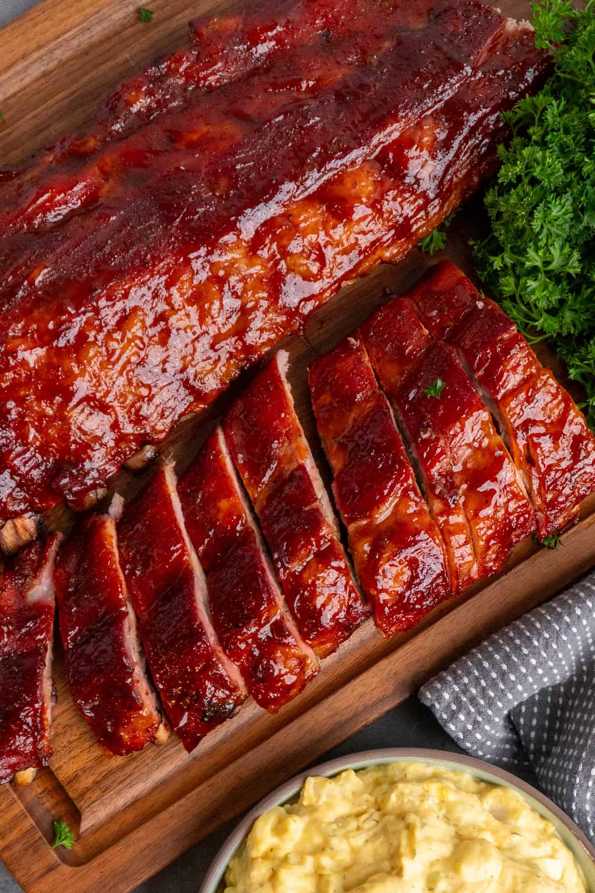Two racks of smoked baby back ribs on a wood cutting board.