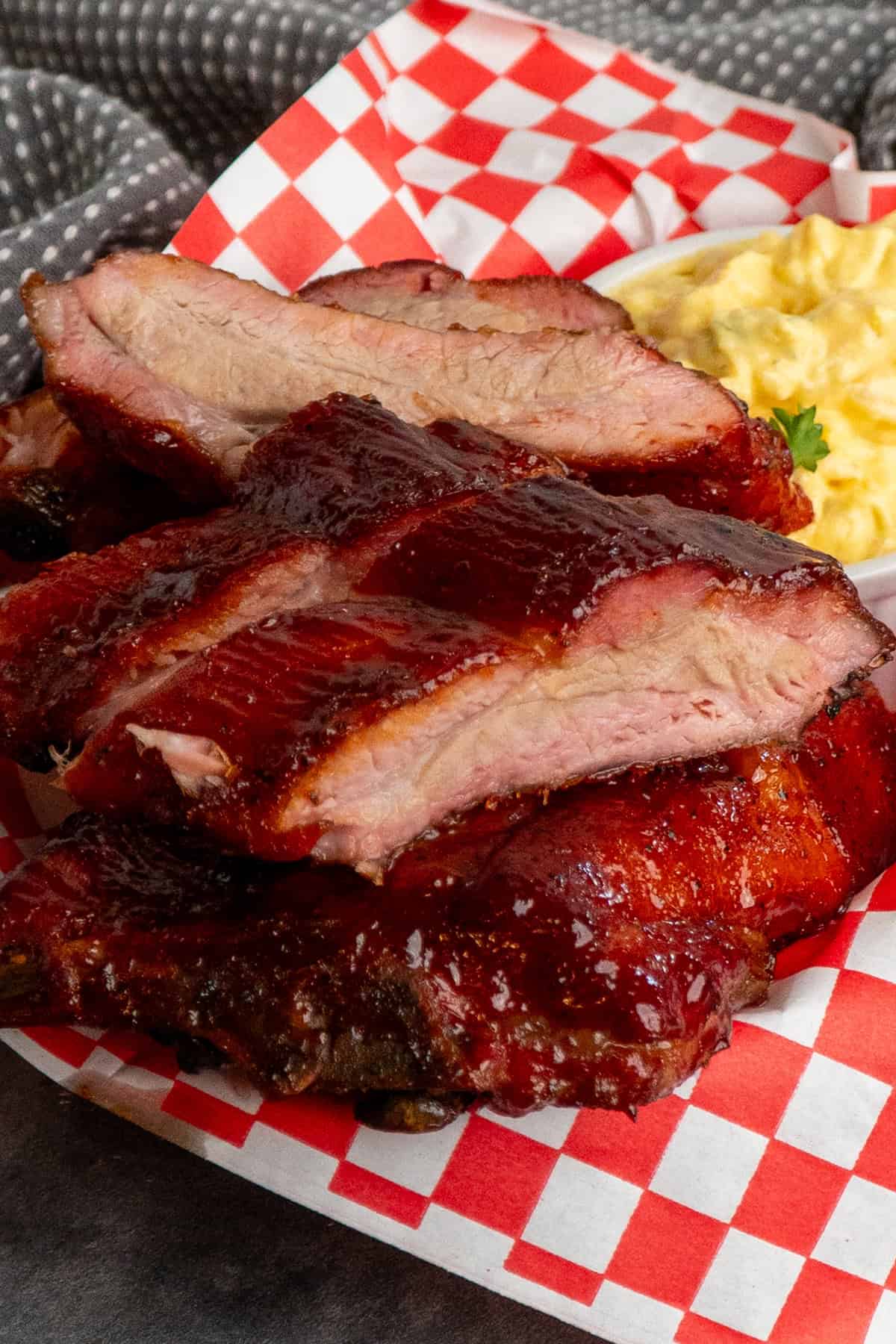 Smoked baby back ribs in a food basket with a side of potato salad.