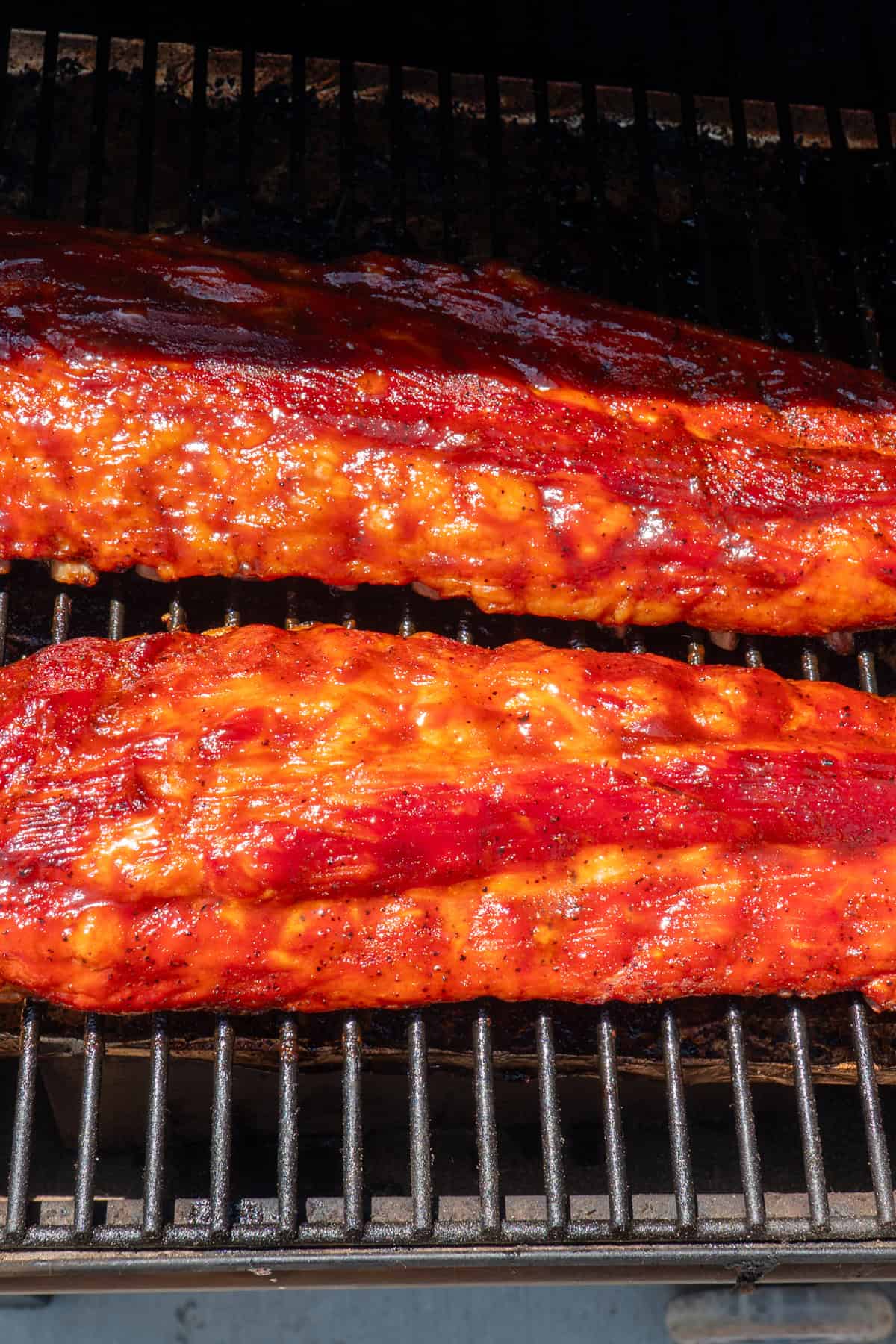 Smoked baby back ribs coated in BBQ sauce and ready to be smoked to completion.