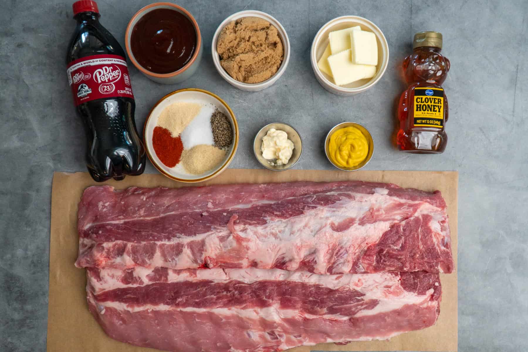 Ingredients to make smoked baby back ribs on a gray countertop.