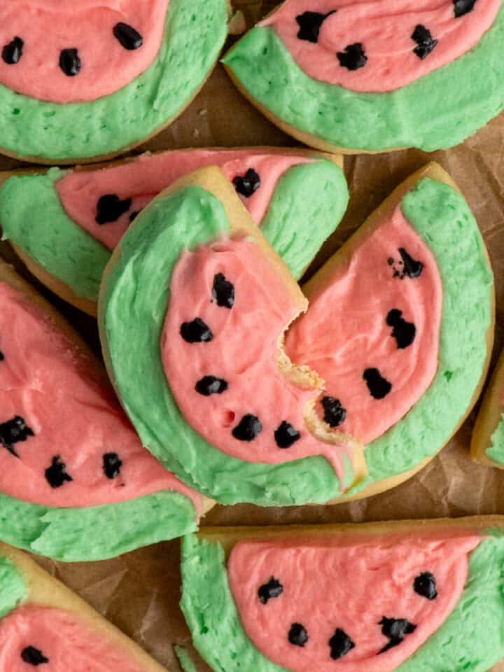 Watermelon sugar cookies stacked up on parchment paper.