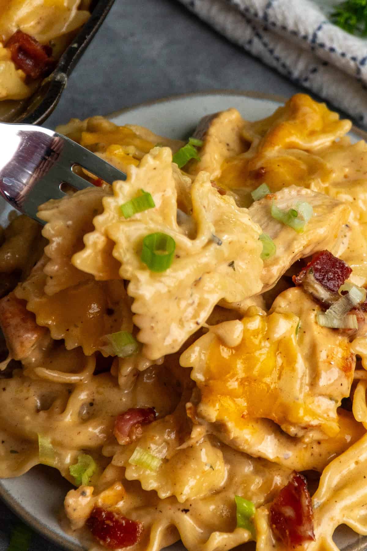 A fork holding a bite of crack chicken pasta.