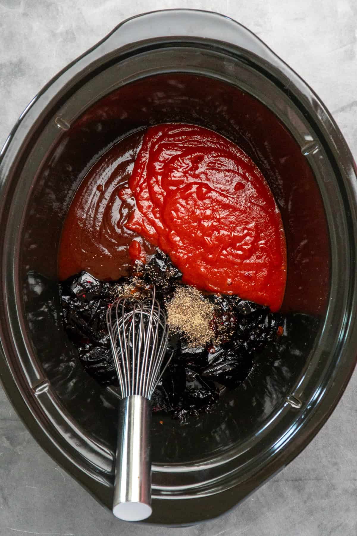 Barbecue sauce, grape jelly, chili sauce, and black pepper mixed together in a crock pot.