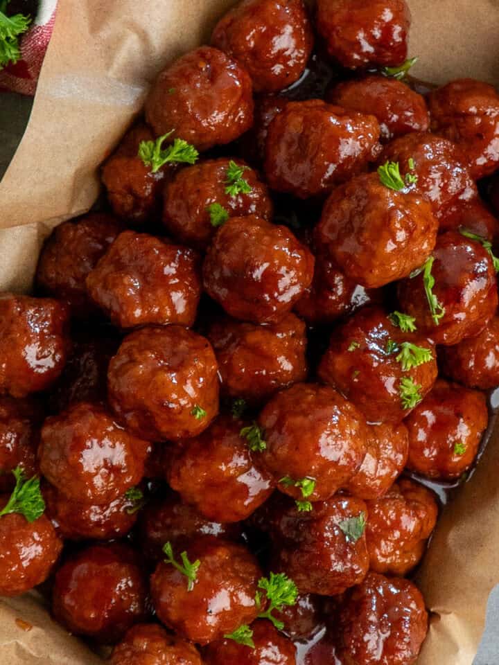 Grape jelly meatballs on a tray covered in parchment paper.