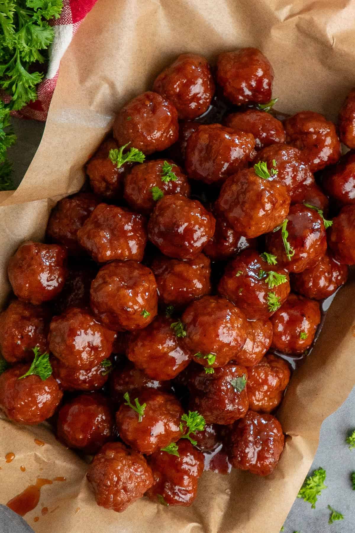 Grape jelly meatballs on a tray covered in parchment paper.