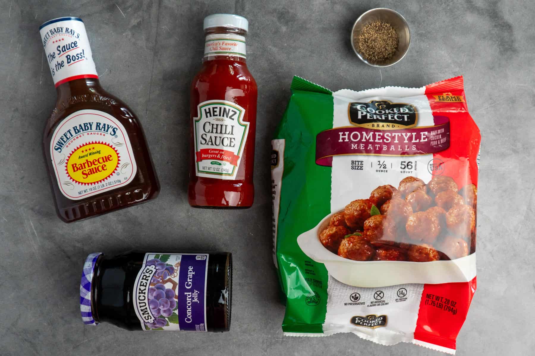 Ingredients to make grape jelly meatballs on a gray stone countertop.