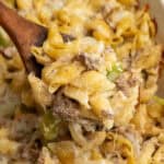 A wooden spoon holding a scoop of Philly cheesesteak casserole.