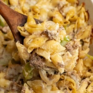 A wooden spoon holding a scoop of Philly cheesesteak casserole.