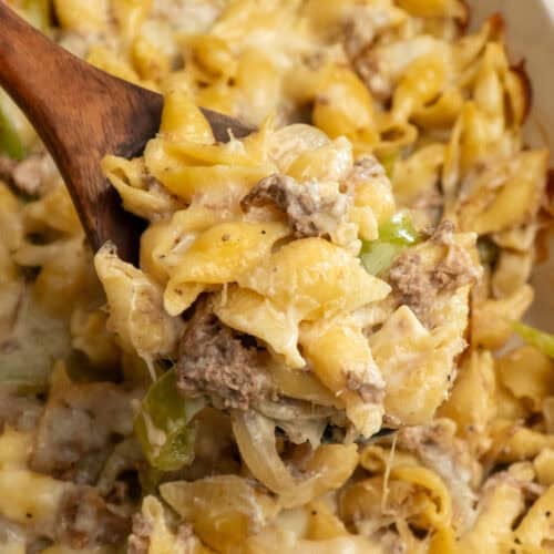 A wooden spoon holding a scoop of Philly cheesesteak casserole.