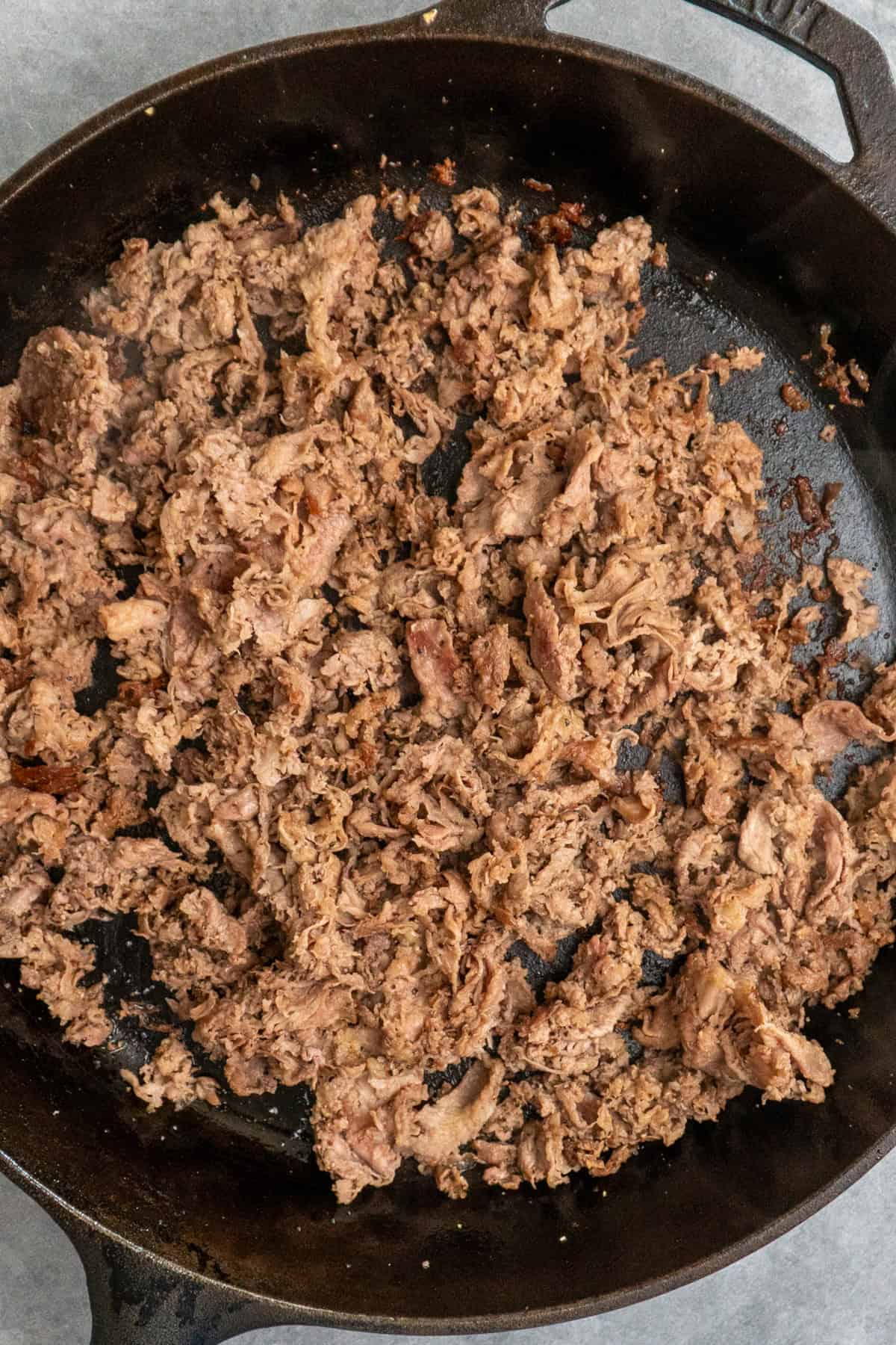 Seasoned and cooked shaved steak in a skillet.