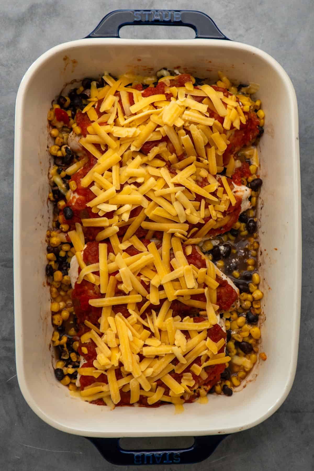 Baked salsa chicken in a baking dish with cheese on top.