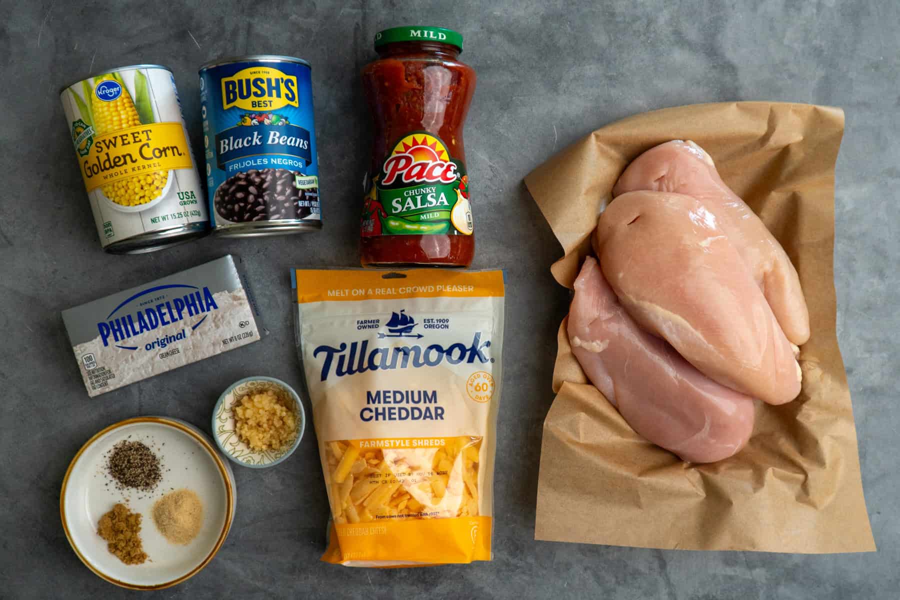Ingredients to make salsa chicken on a gray countertop.