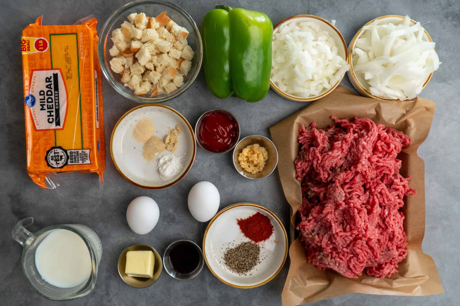 Ingredients to make Philly cheesesteak meatloaf on a gray countertop.