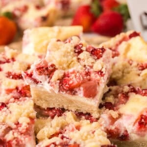 Strawberry cheesecake bars cut into squares and stacked.