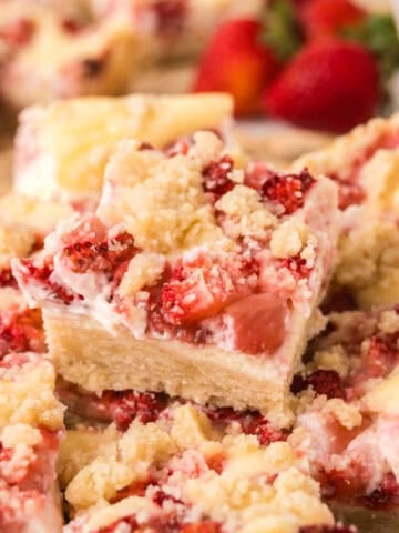 Strawberry cheesecake bars cut into squares and stacked.