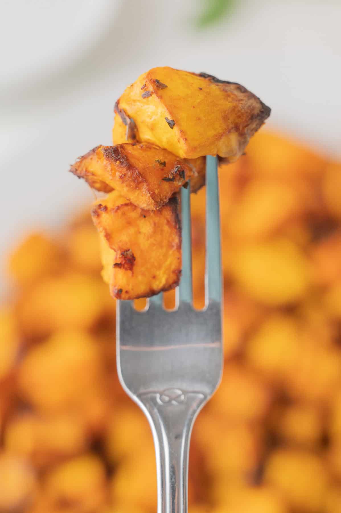 A few pieces of squash on a fork being held up in the air.