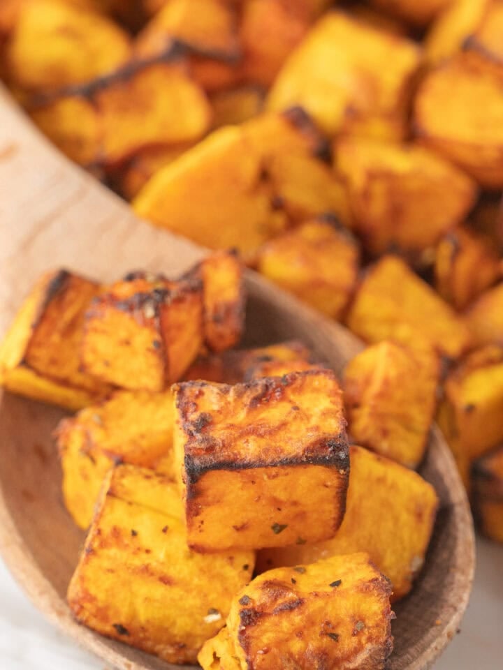 Air fryer butternut squash scooped with a wooden spoon.