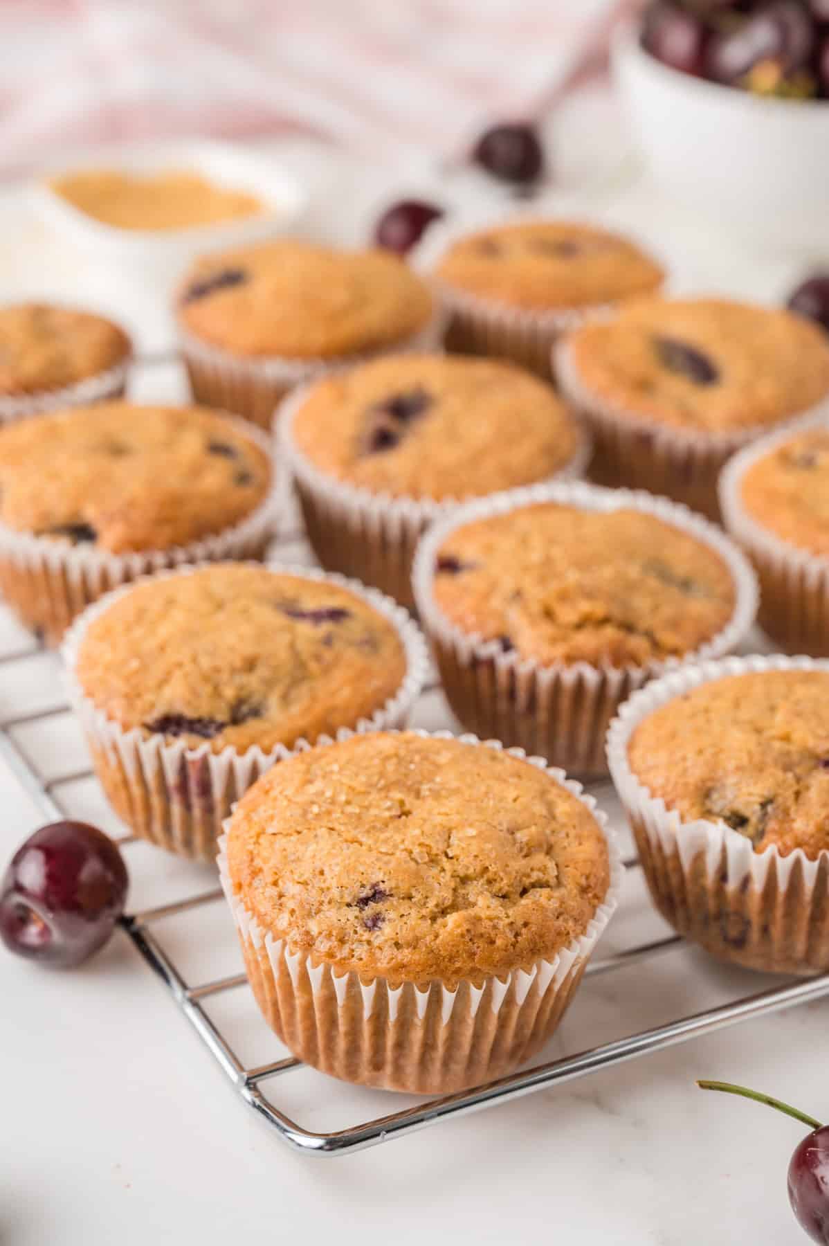Muffins with cherries on a cooling rack.