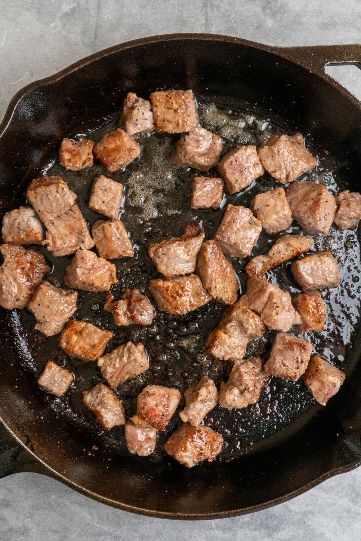 Cooked steak bites in a cast iron skillet.