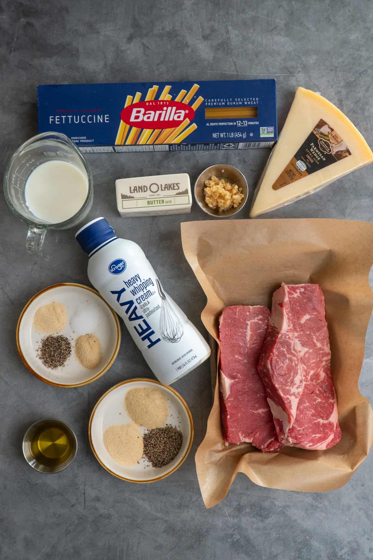 Ingredients to make steak fettuccine alfredo on a gray countertop.
