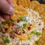 A hand holding a cracker covered in million dollar dip.