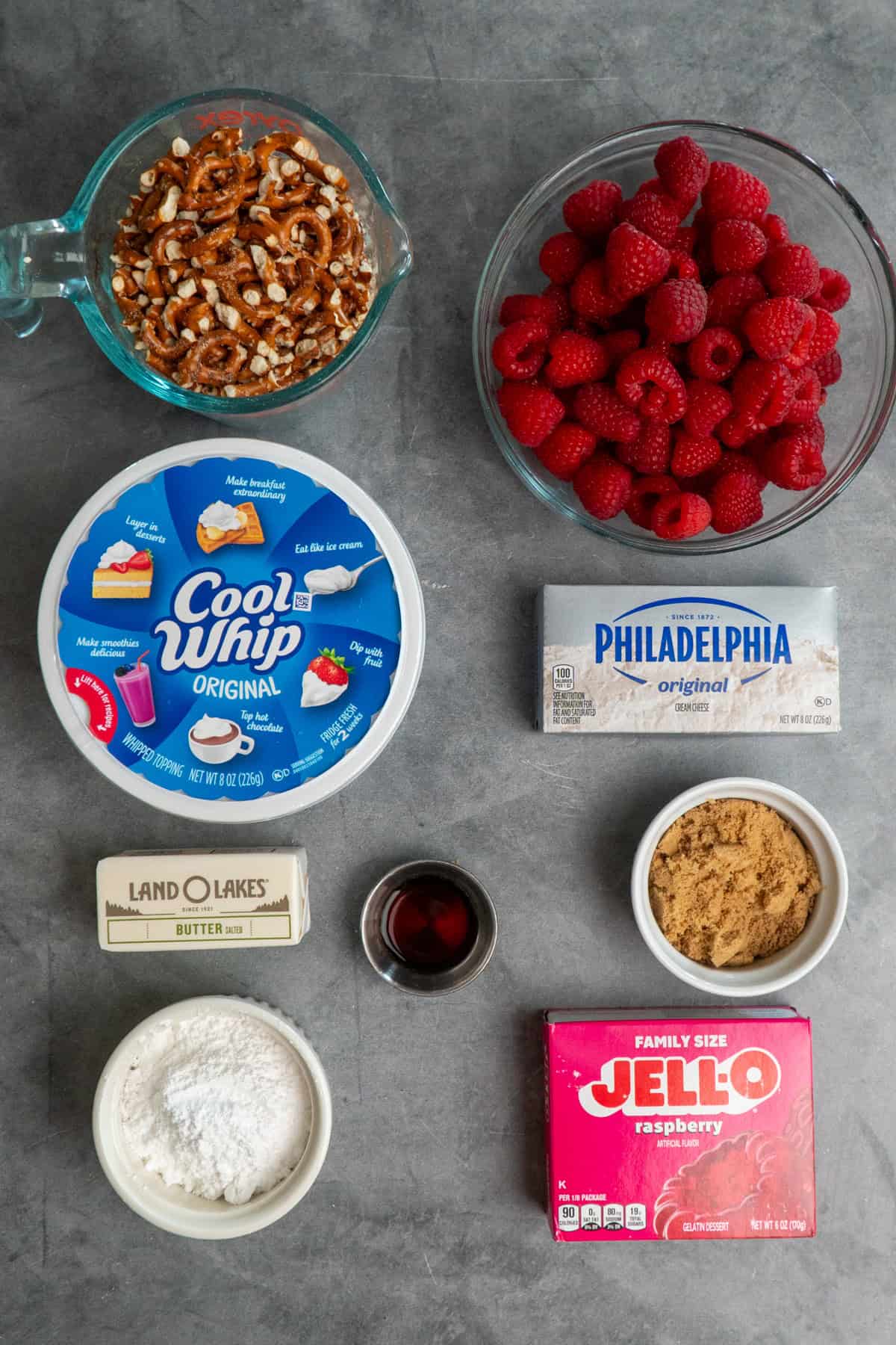 All the ingredients to make raspberry pretzel salad on a gray countertop.