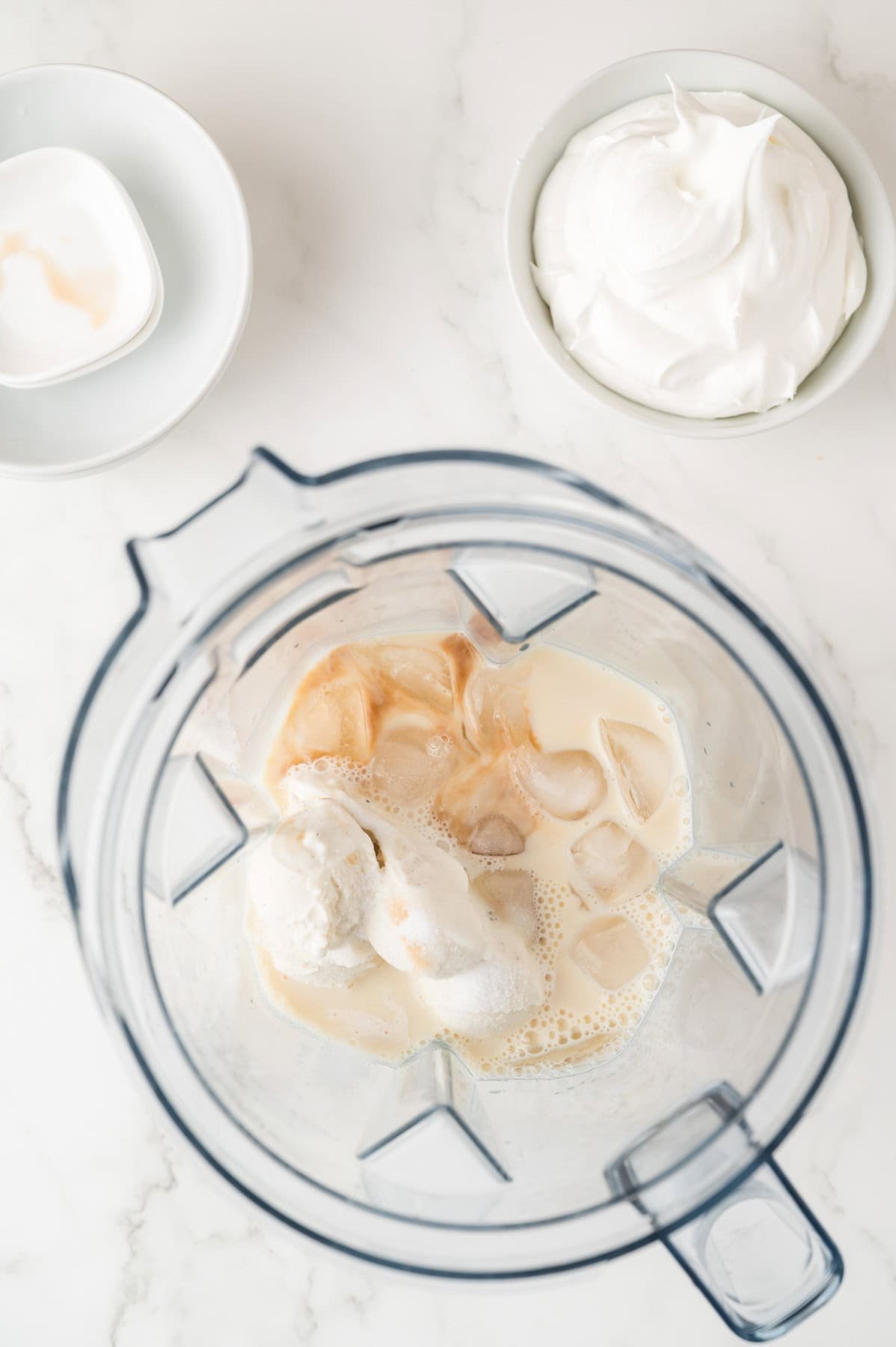 Ice, milk, vanilla bean ice cream, sugar, and vanilla extract in a blender.