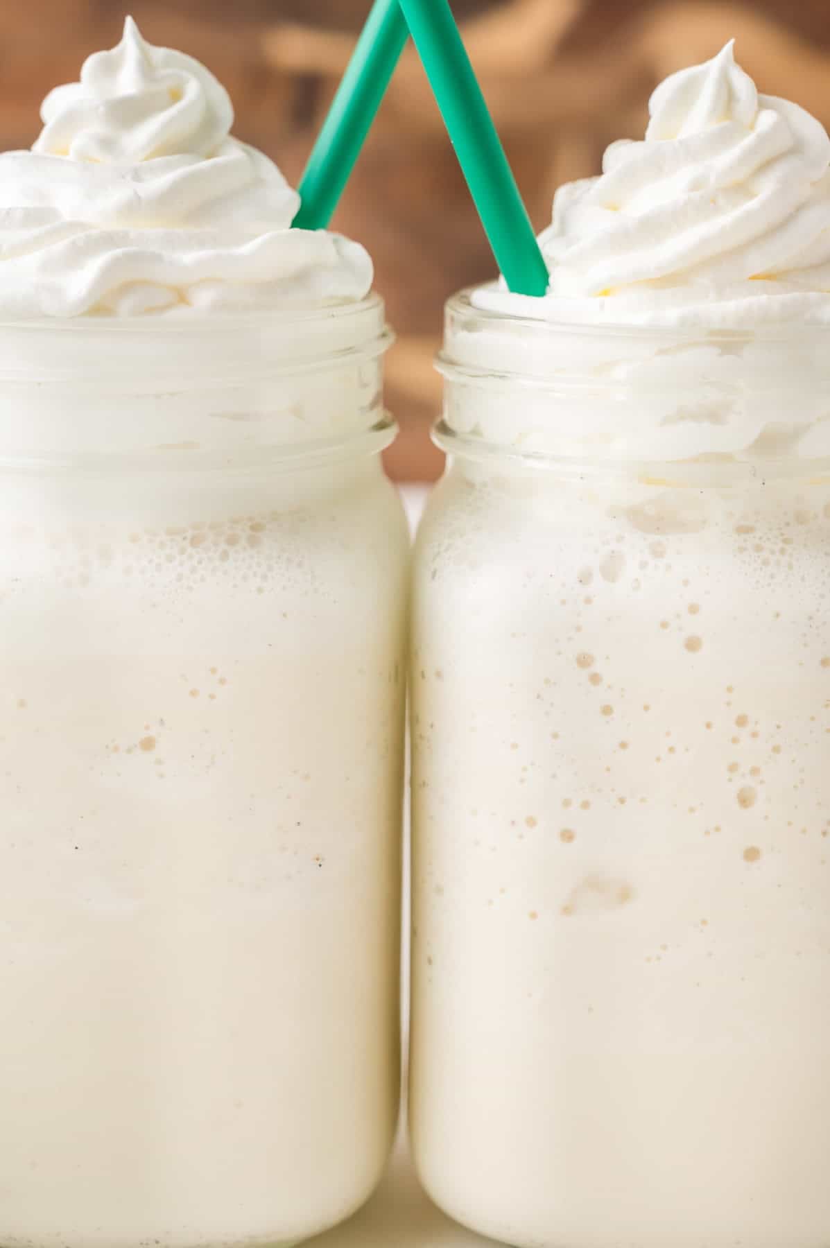 Two glasses full of frappuccino with whipped cream.