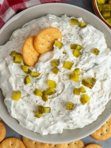 Dill pickle dip in a bowl topped with chopped pickles.