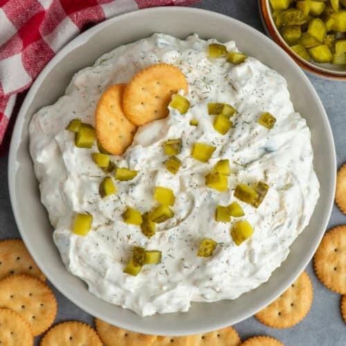 Dill pickle dip in a bowl topped with chopped pickles.