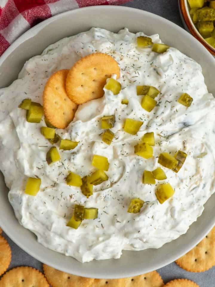 Dill pickle dip in a bowl topped with chopped pickles.