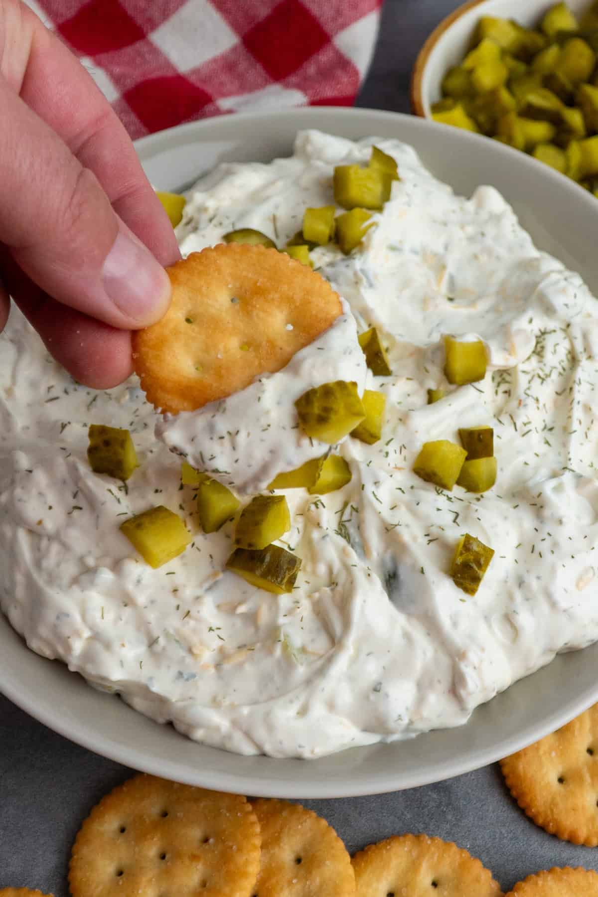 A cracker being dipped into the pickle dip.