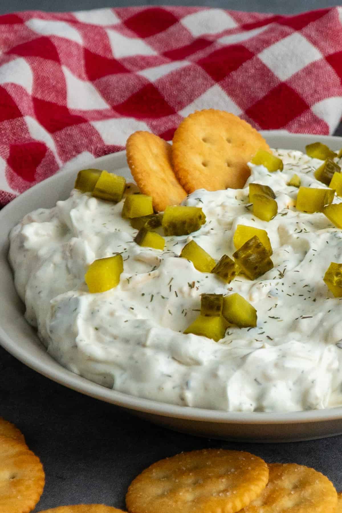 Dill dip in a bowl with pickles on top.
