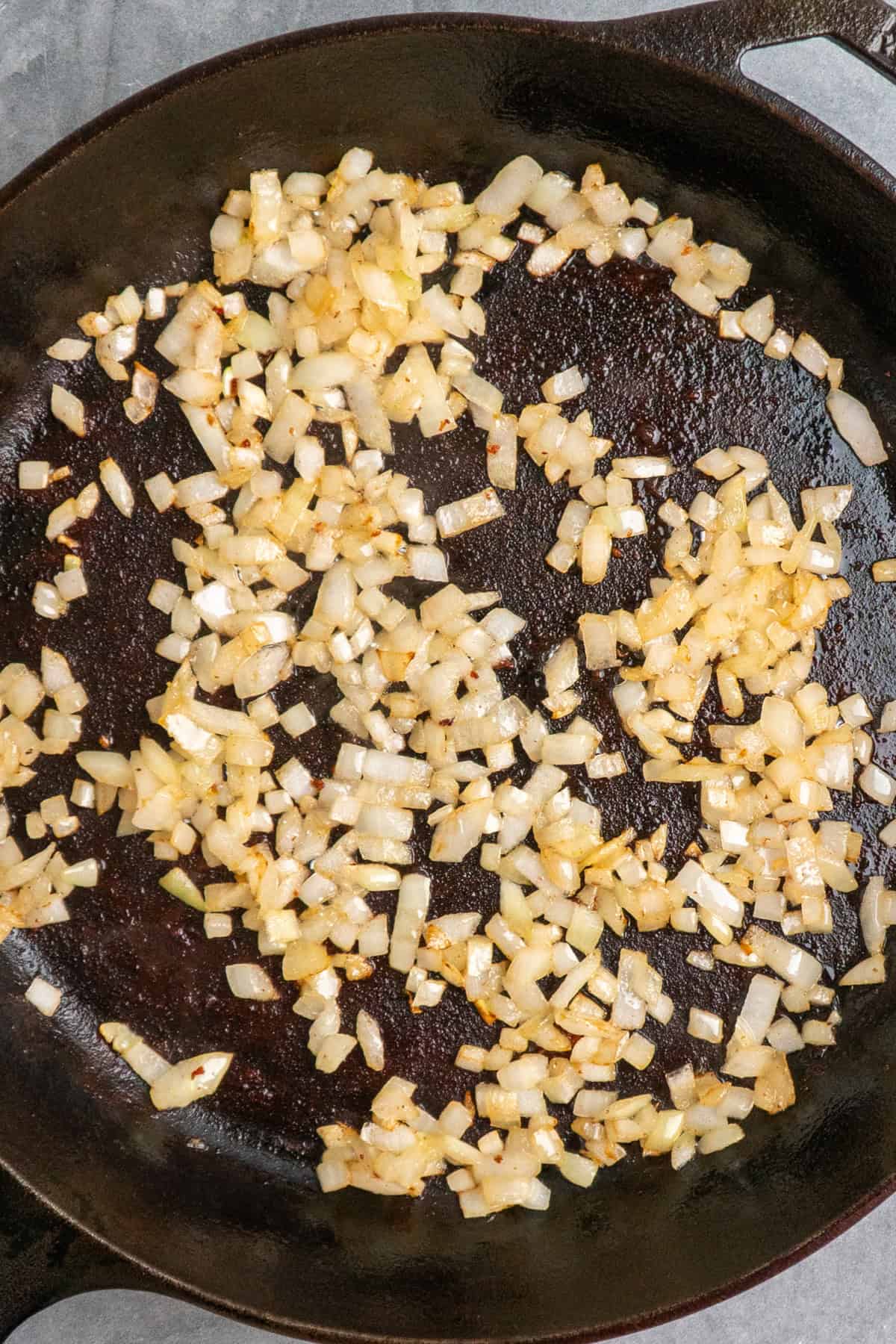 Onions sautéing in bacon grease in a cast iron skillet.