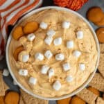 Pumpkin fluff dip in a white bowl with nilla wafers and graham crackers around it.