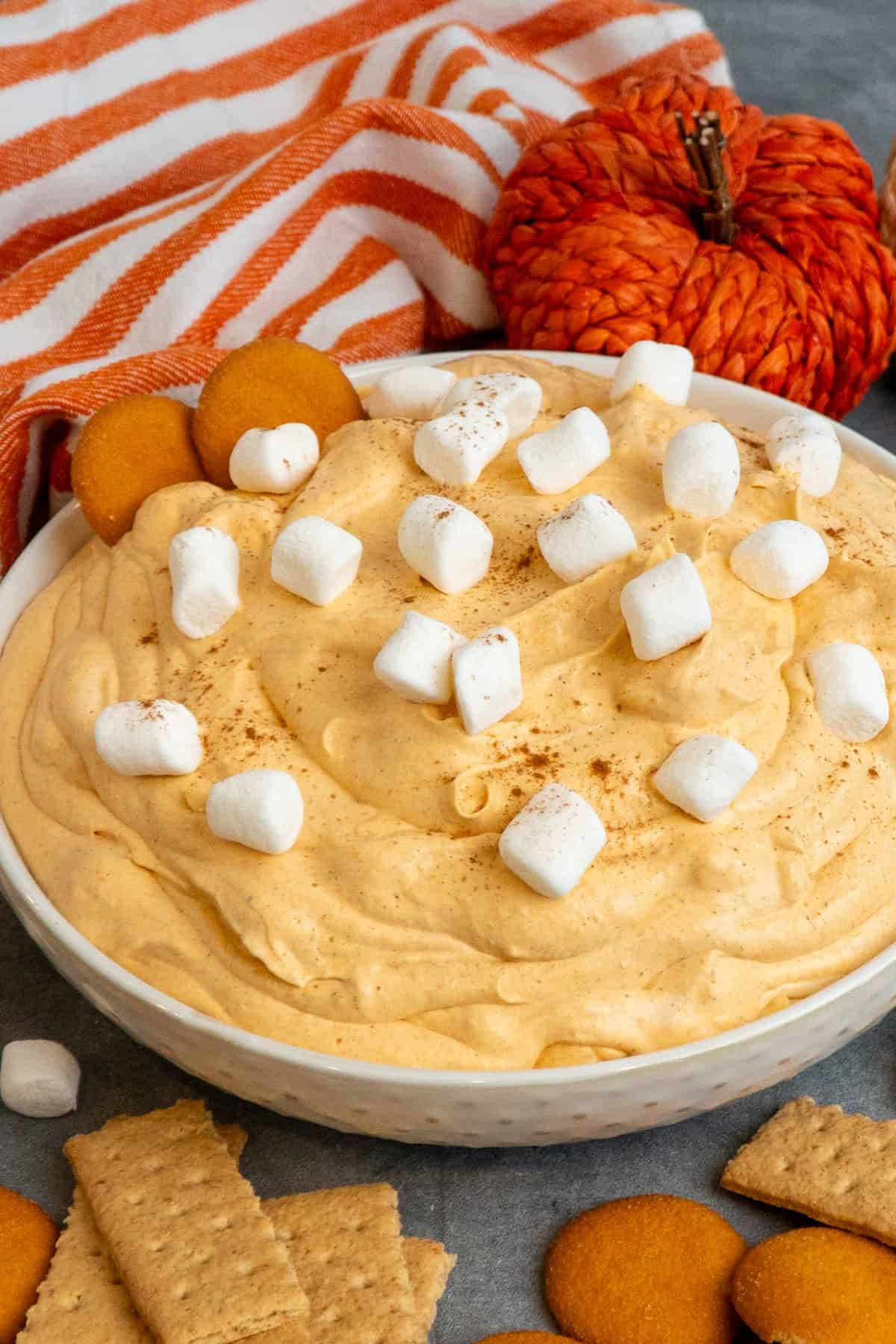 Pumpkin fluff dip in a white bowl with nilla wafers and graham crackers around it.