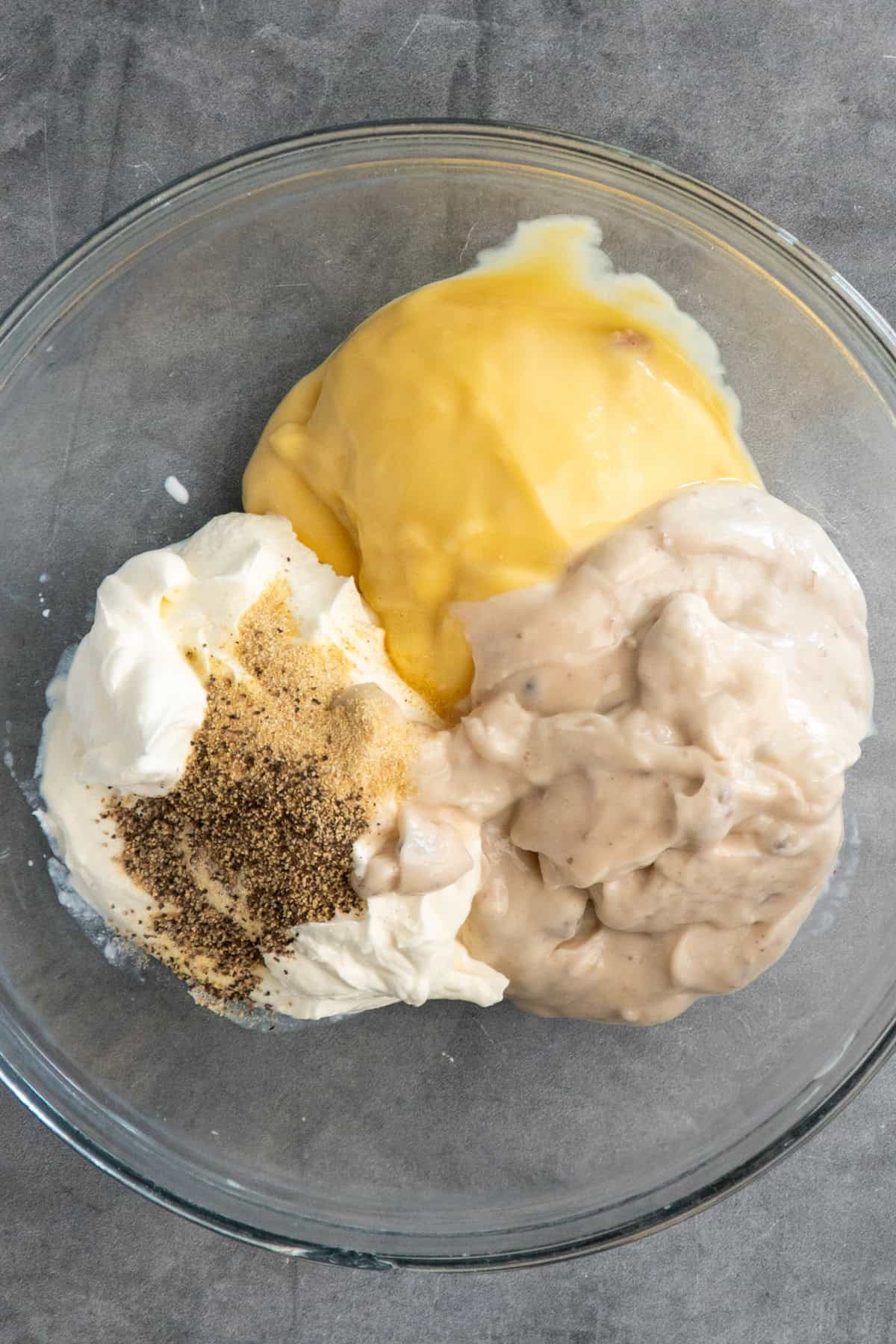 Sour cream, cream of chicken soup, cream of mushroom soup, and seasonings in a bowl.