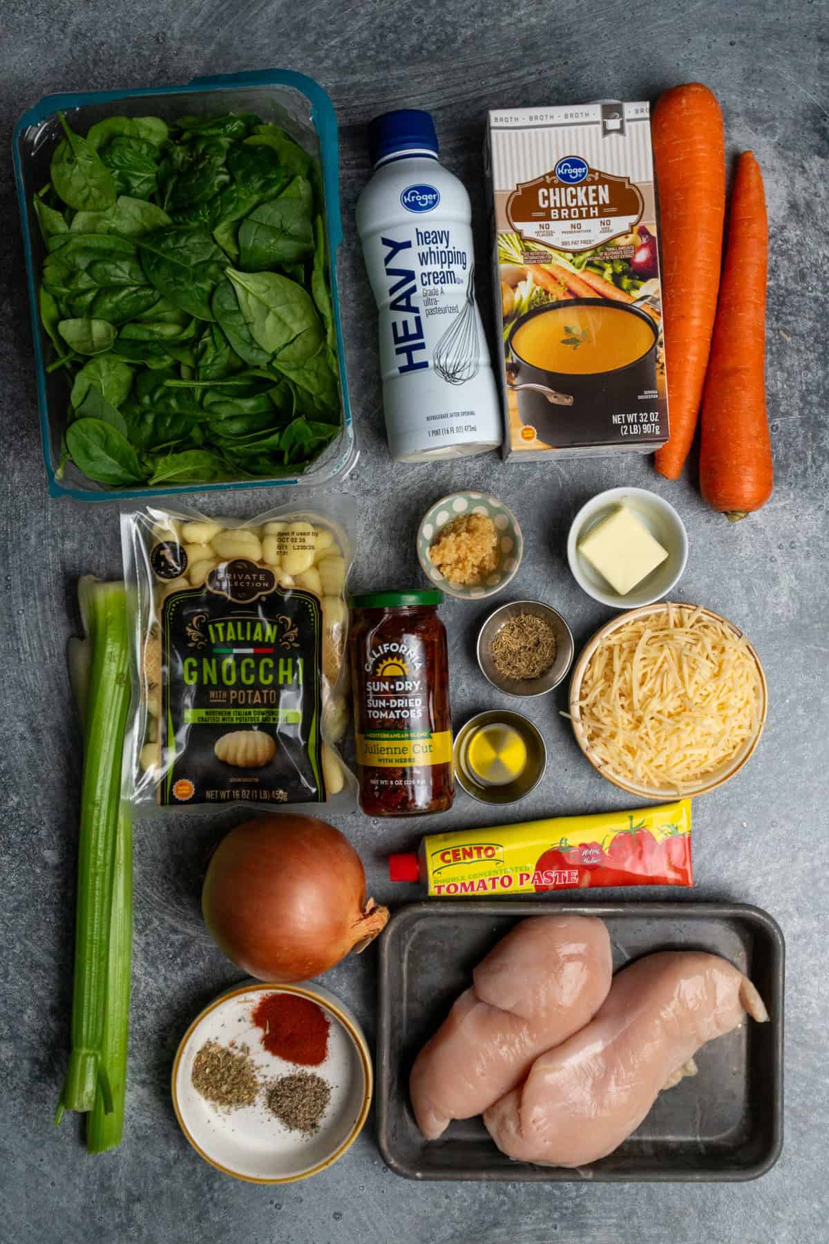 Ingredients for chicken gnocchi soup on a gray countertop.