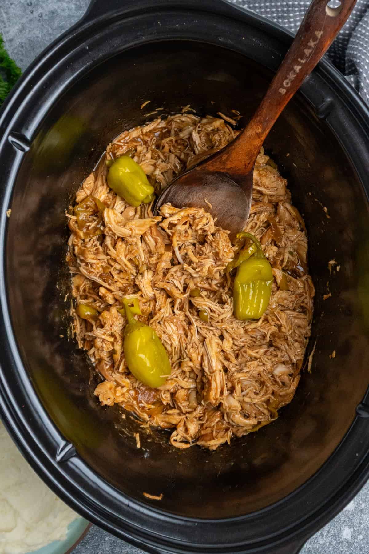 Mississippi chicken in a Crock Pot with a wooden spoon and ready to eat.