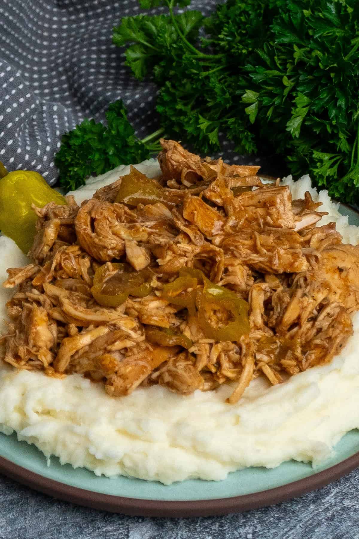 Crock Pot Mississippi chicken over a plate of mashed potatoes.