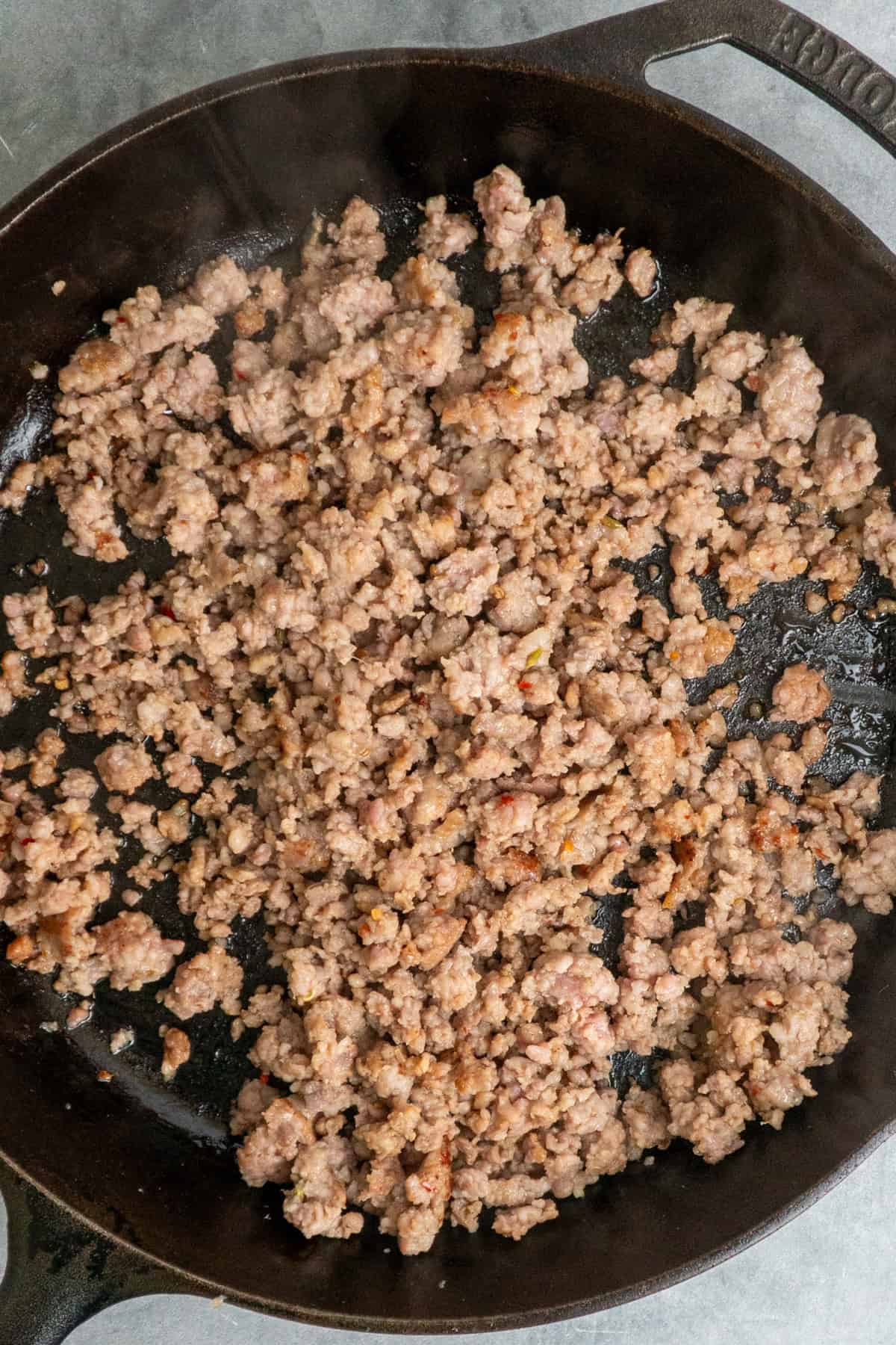 Sausage cooking in a cast iron skillet.